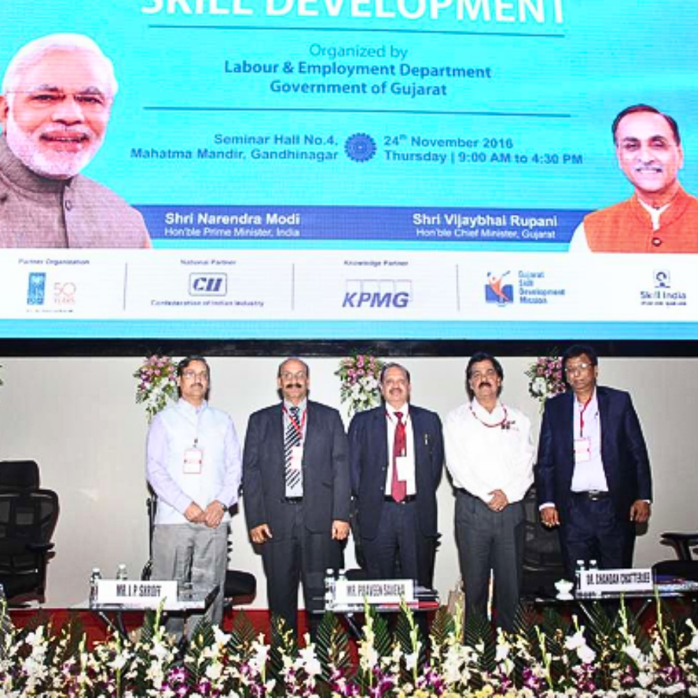 Screen displaying a seminar event with speakers and a banner about skill development in Gujarat.