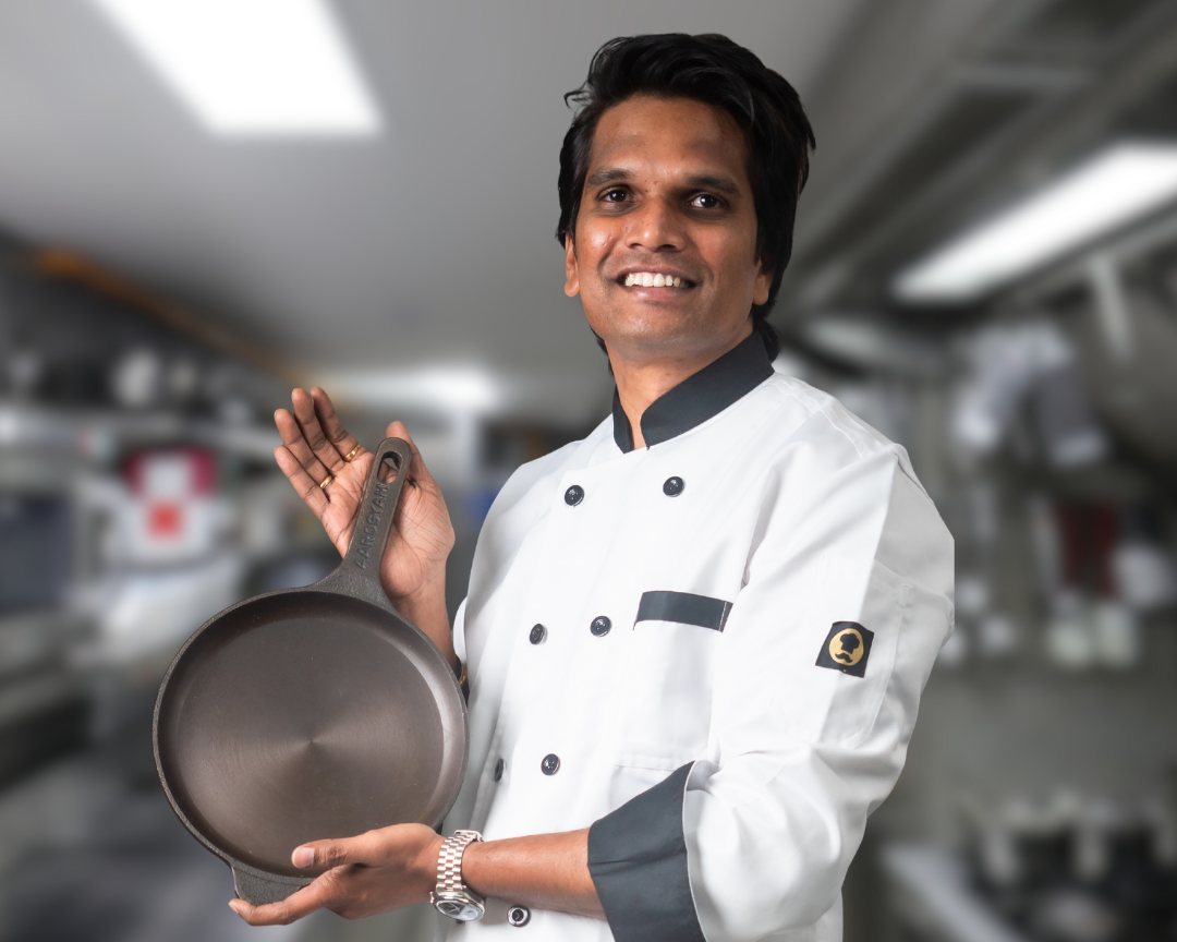 Chef holding a cast iron frying pan in a kitchen setting