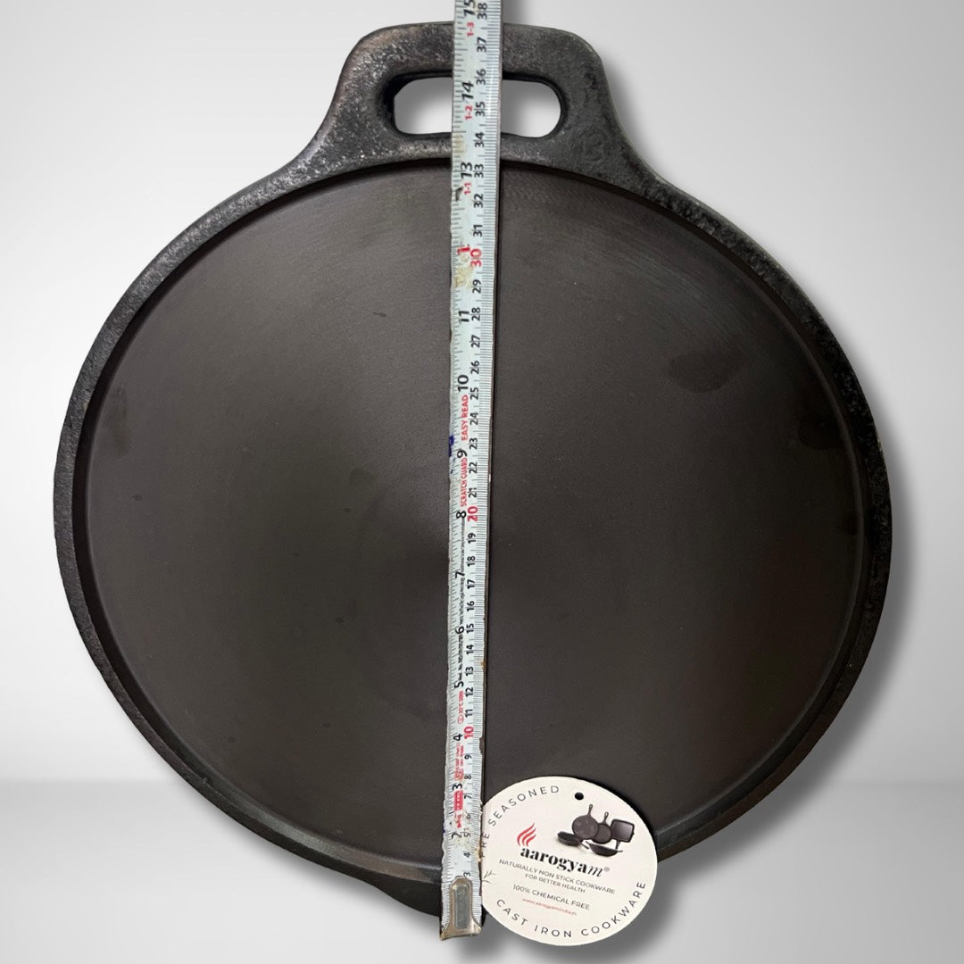 Black cast iron skillet with a measuring tape for scale on a gray background