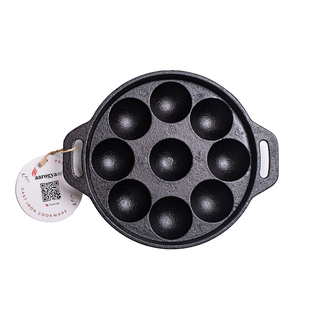 Black cast iron pan with round compartments on a white background