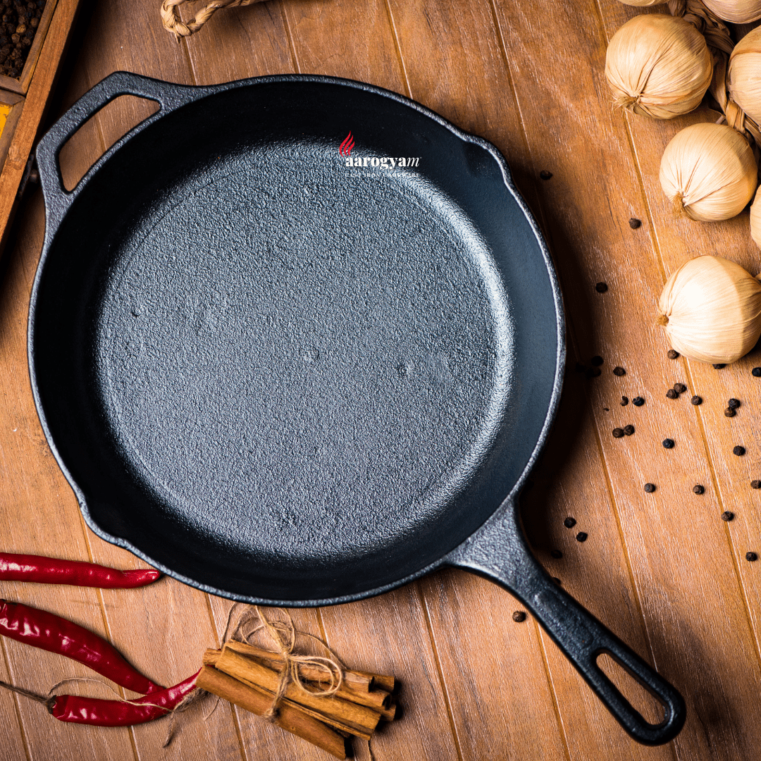 Black cast iron skillet on a wooden surface with spices and ingredients
