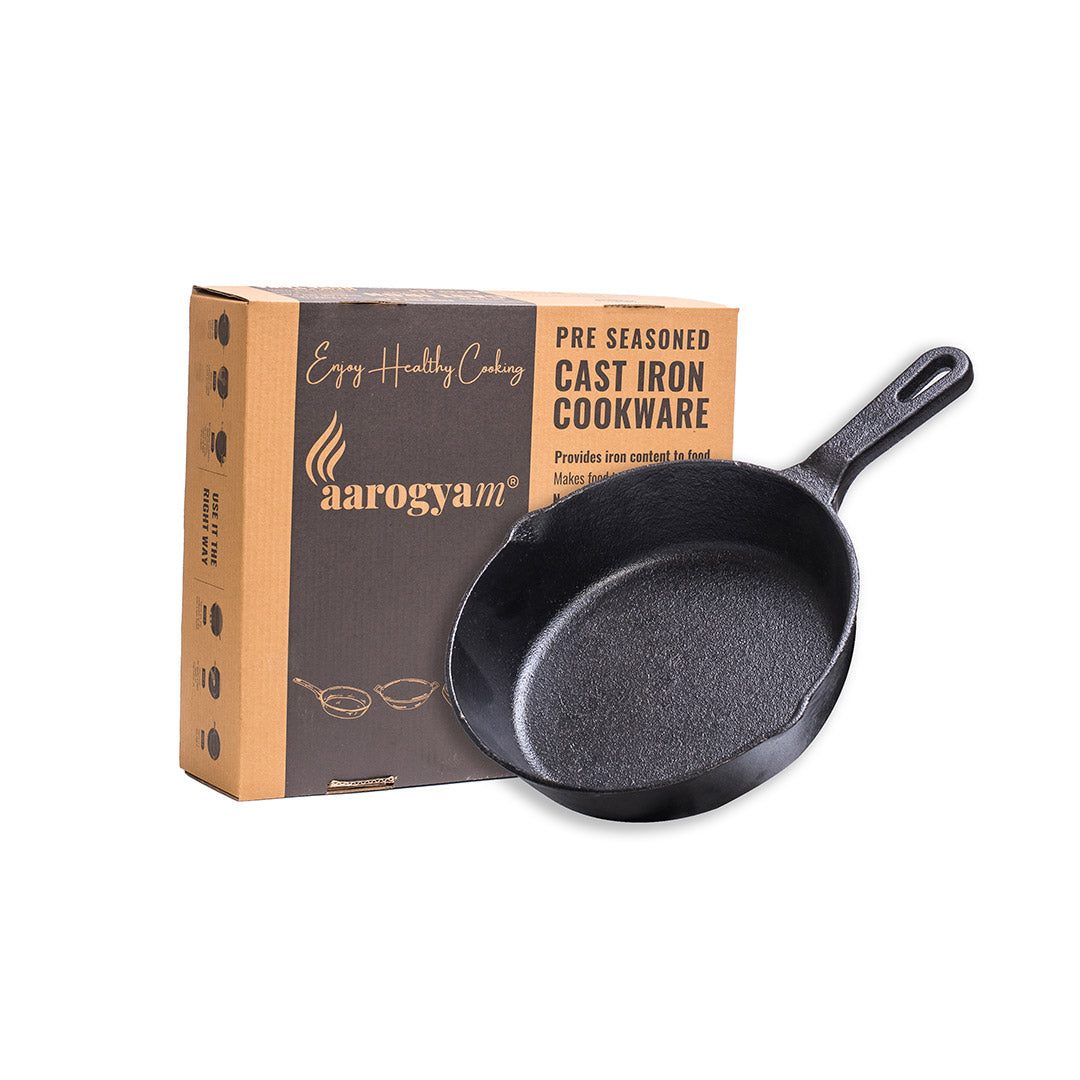 Black cast iron skillet with Aarogyam packaging on a white background