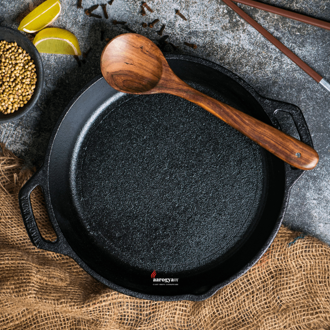 Black cast iron skillet with wooden spoon on a rustic surface