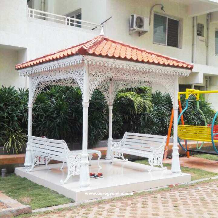 a white gazebo with a red roof and a yellow swing in front of a building