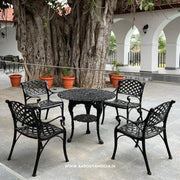 Outdoor patio set with black metal chairs and table near a large tree