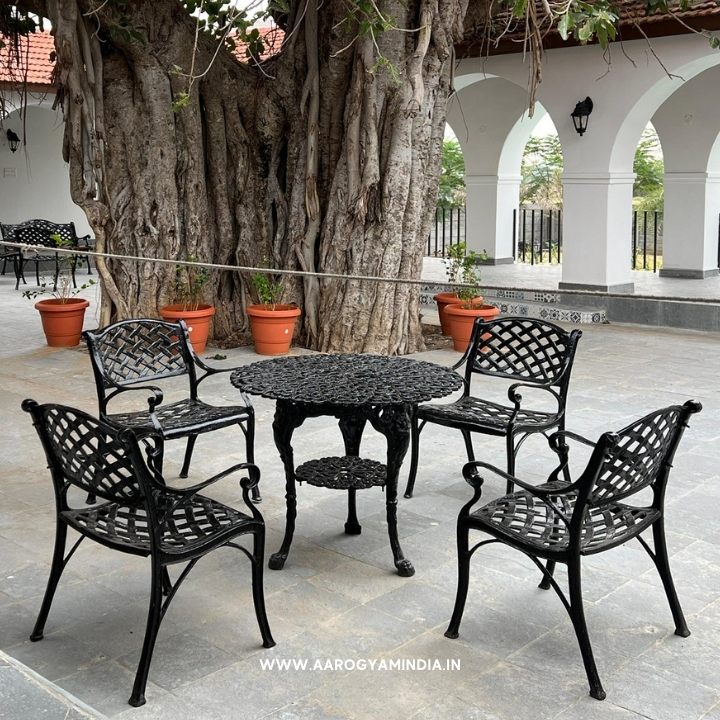 Outdoor patio set with black metal chairs and table near a large tree