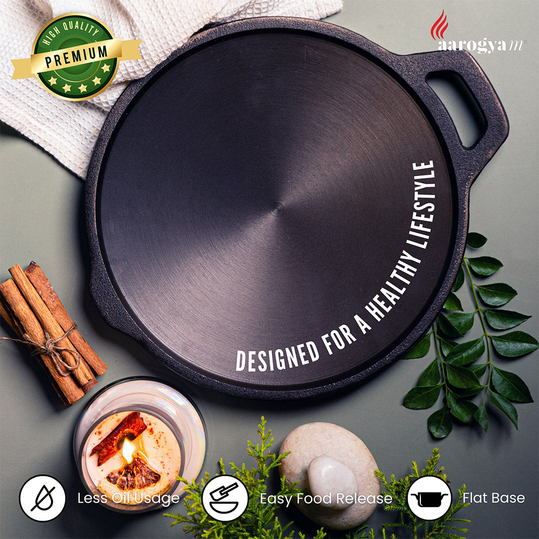Cast iron skillet with 'Aarogyam' branding and text on a gray background with cinnamon sticks and leaves.