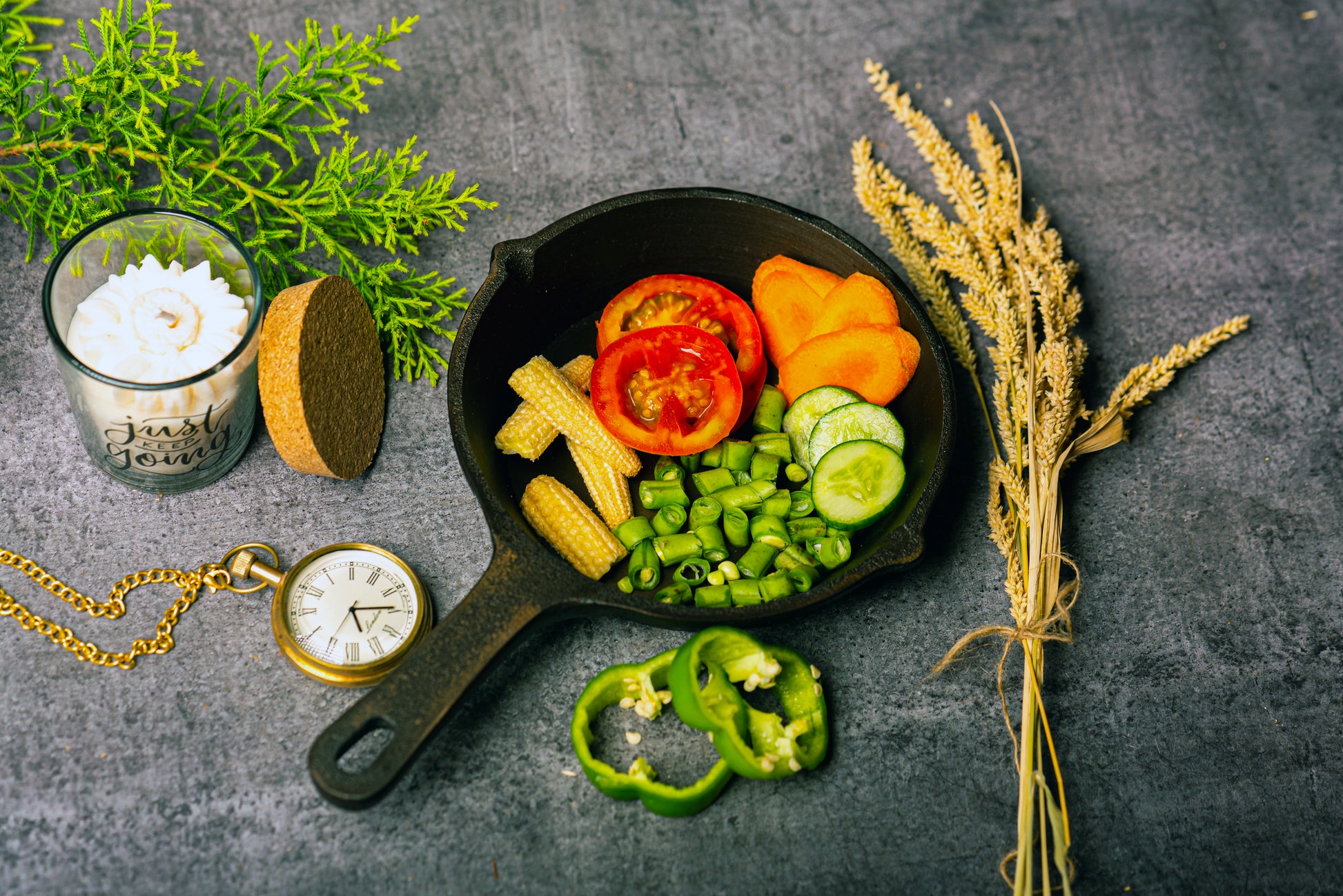 Frying pan with sliced vegetables on a dark surface with decorative elements.