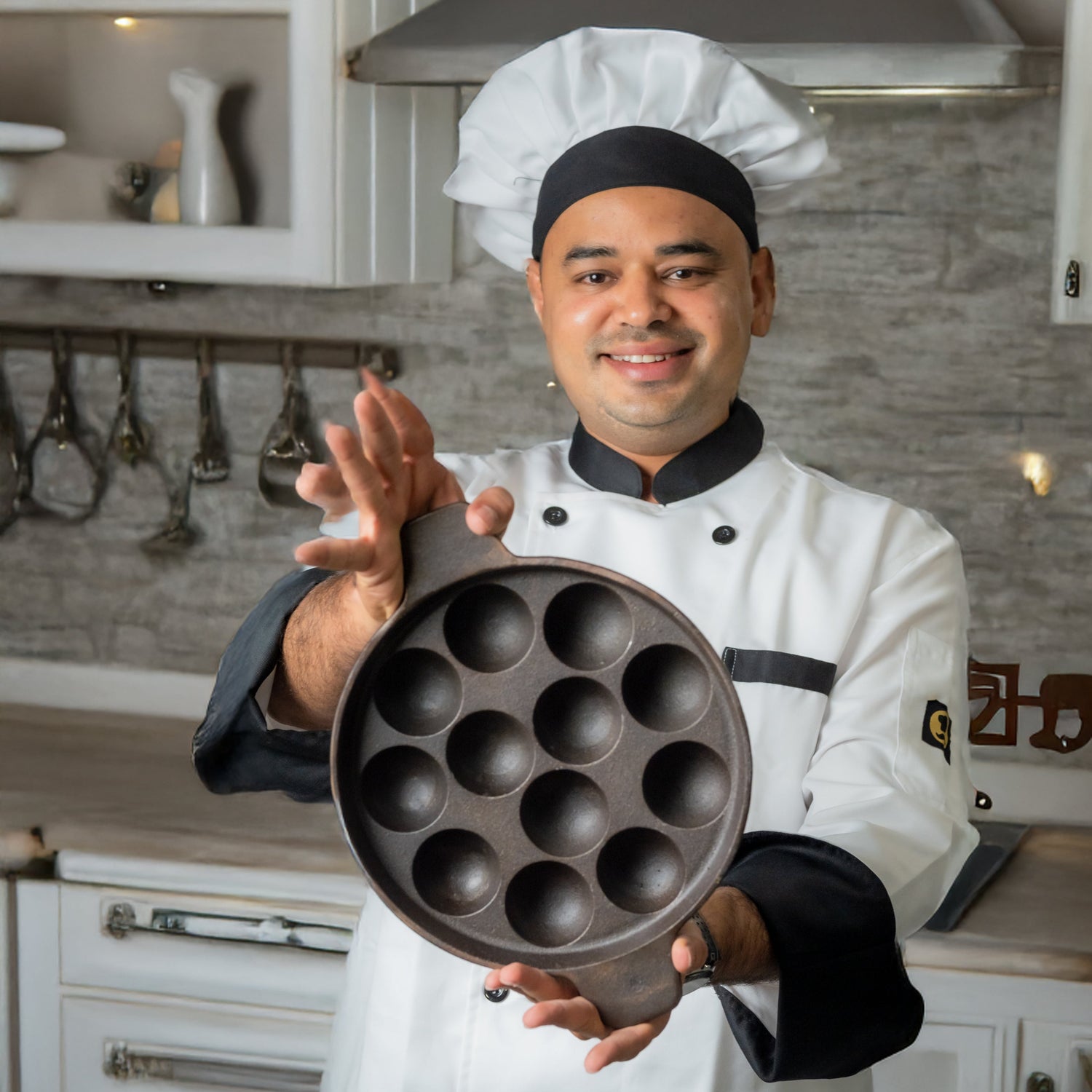 Chef holding an aarogyam cast iron pnaiyaram pan with 12 pits in a kitchen setting

