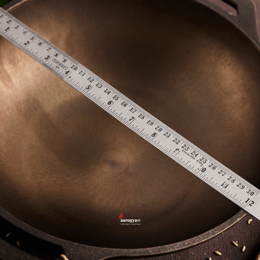 Measurement of a cast iron skillet using a ruler with 'Aarogya' branding.