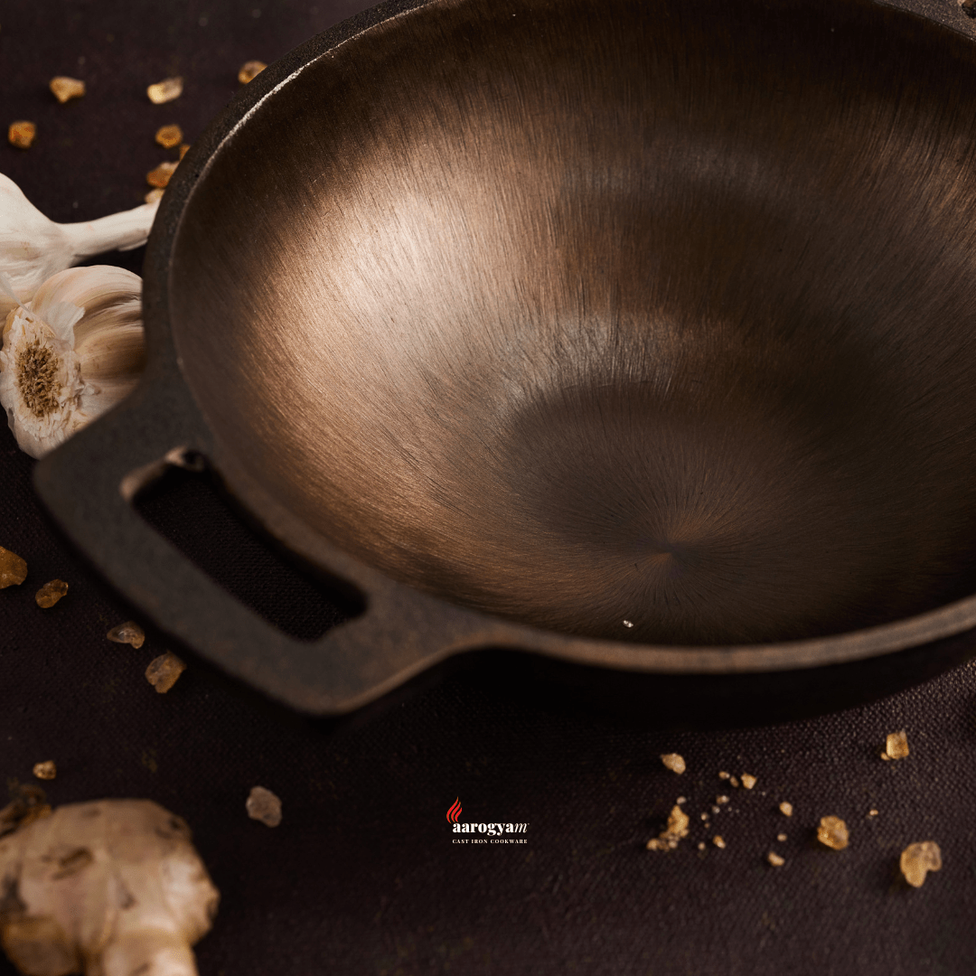 Wooden wok on a dark surface with spices and garlic cloves.