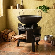 Black metal stove with a pot on top, surrounded by wooden logs and kitchen utensils.