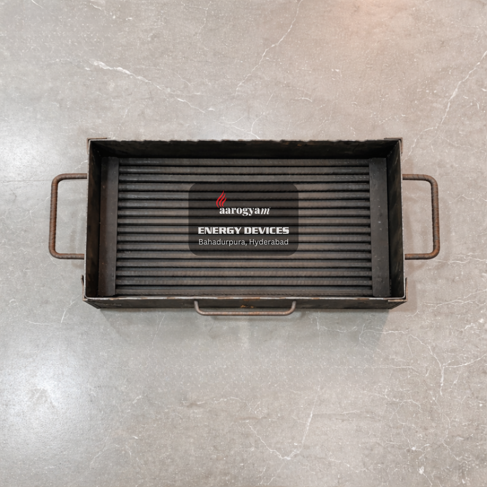 Black grill pan with handles on a gray surface, featuring the Aarogyam Energy Devices logo.