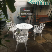 White outdoor furniture set with a sign for Aarogyam Energy Devices in the background.