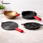 Set of cast iron cookware with red handles on a light surface, branded 'aarogyam'.