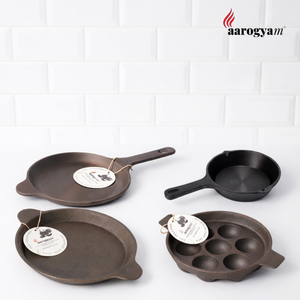 Set of cast iron cookware with 'aarogyam' branding on a white background