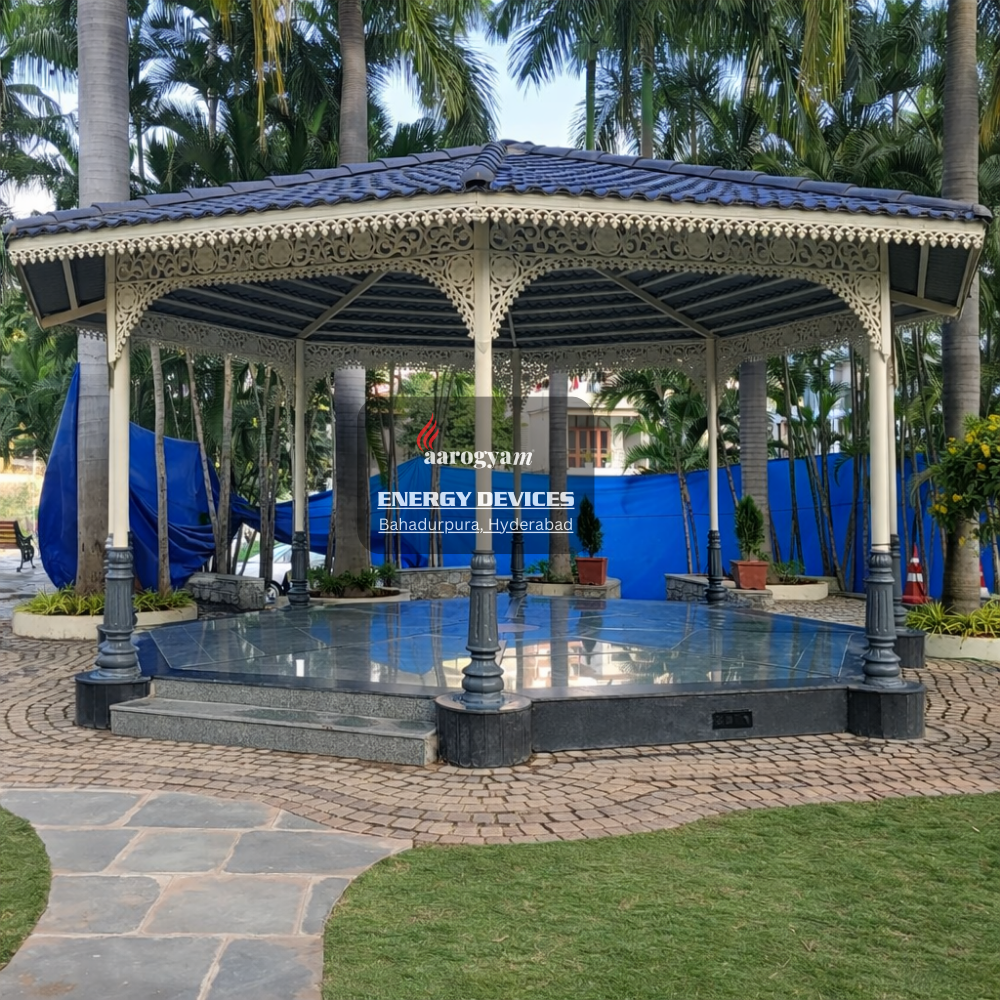 Decorative gazebo with a blue roof in an outdoor setting with palm trees and a blue tarp in the background.