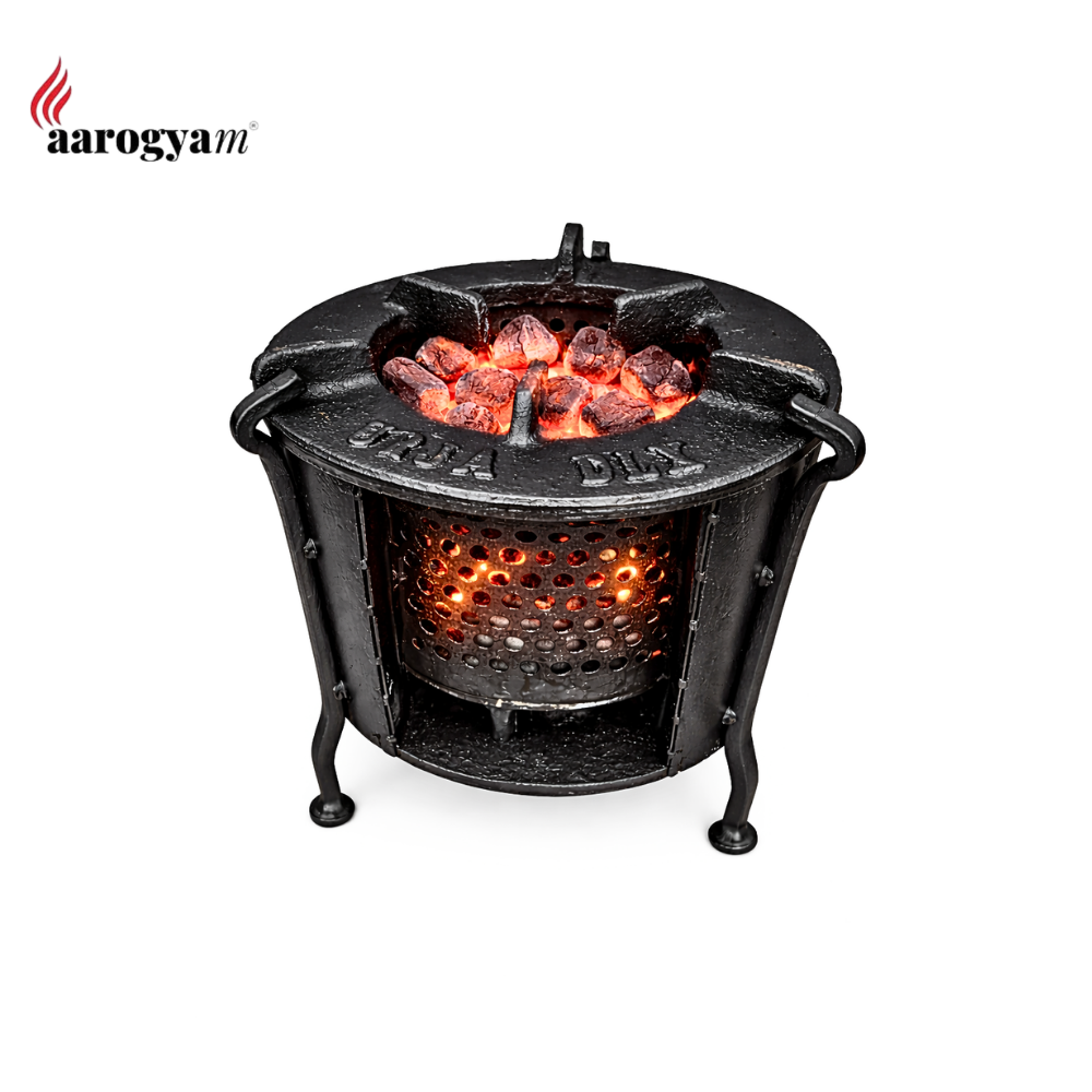 Black cast iron fire pit with glowing embers on a white background, featuring the 'aarogyam' brand.