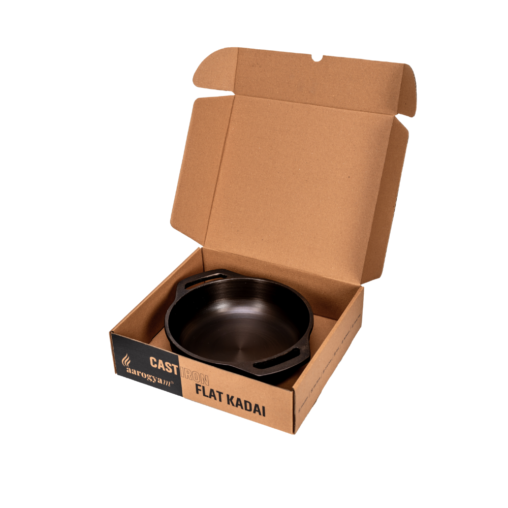 Black flat kadai in an open cardboard box on a white background