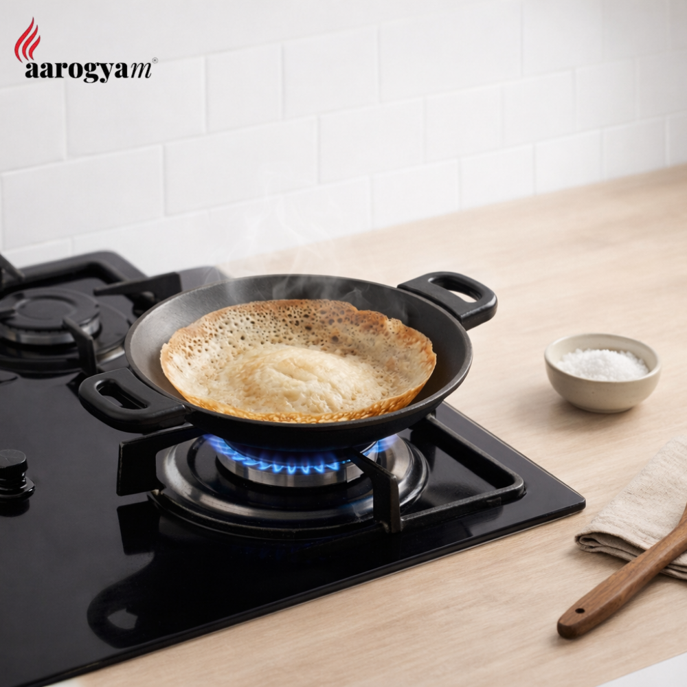 Frying pan with a pancake on a gas stove, brand 'aarogyam' visible