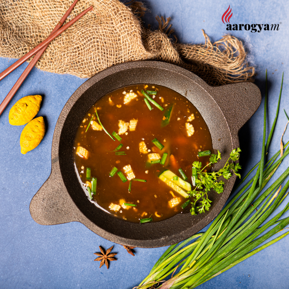 Hot pot dish with ingredients on a blue background, featuring the Aarogyam logo.