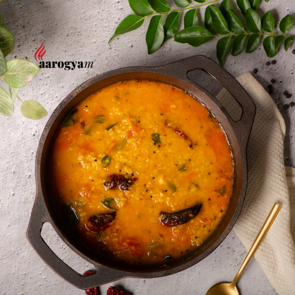 Traditional Indian dish served in a cast iron pan with 'aarogyam' branding.