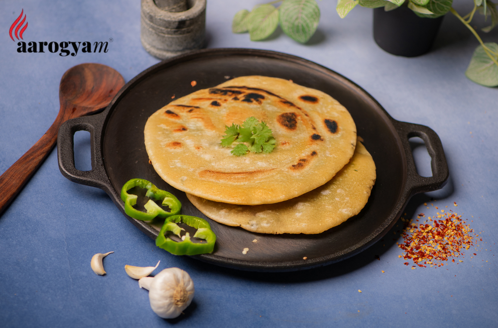 Flatbreads on a black skillet with vegetables on a blue background, featuring the aarogya brand.