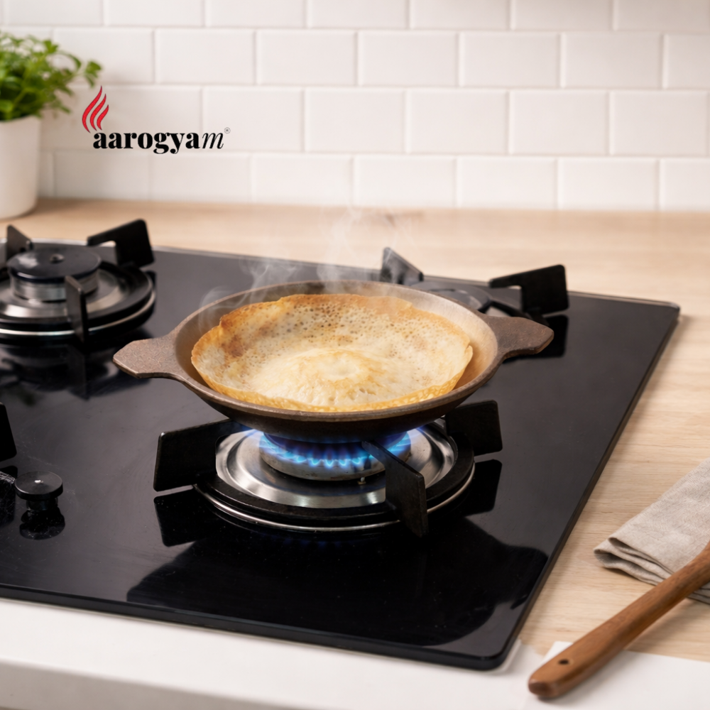 Pan with food on a gas stove in a kitchen setting, featuring the 'aarogyam' brand.