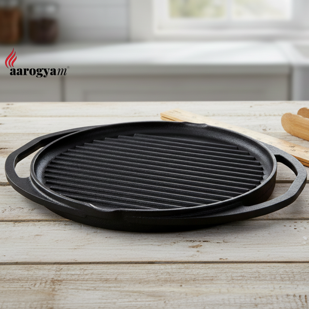 Black cast iron grill pan on a wooden surface with 'aarogya' branding.
