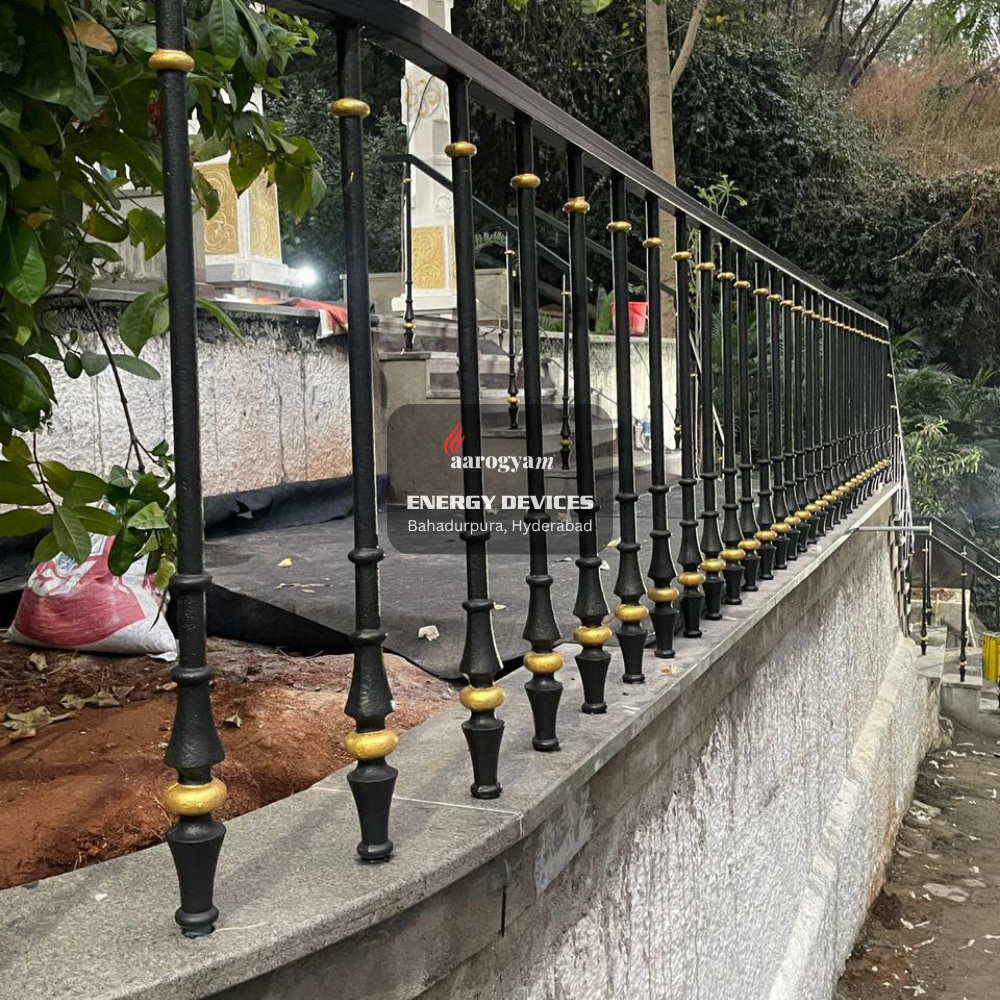 Decorative metal railing with black and gold accents on a concrete ledge.