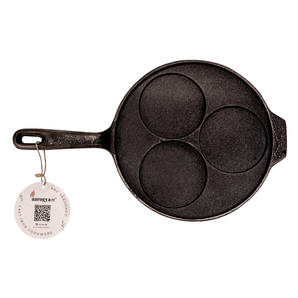 Black cast iron pancake pan with three circular compartments on a white background