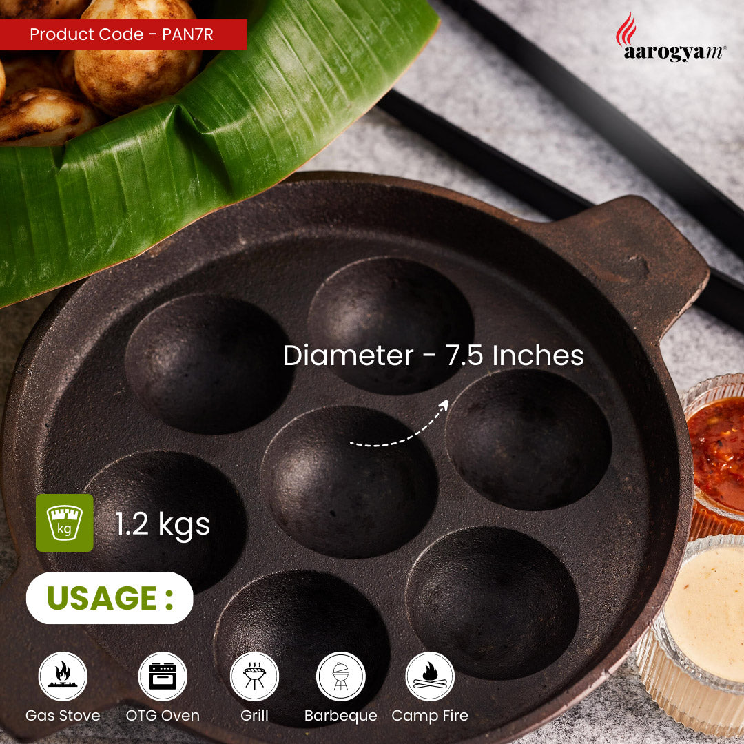 Cast iron pan with multiple compartments on a gray surface, featuring Aarogya brand.