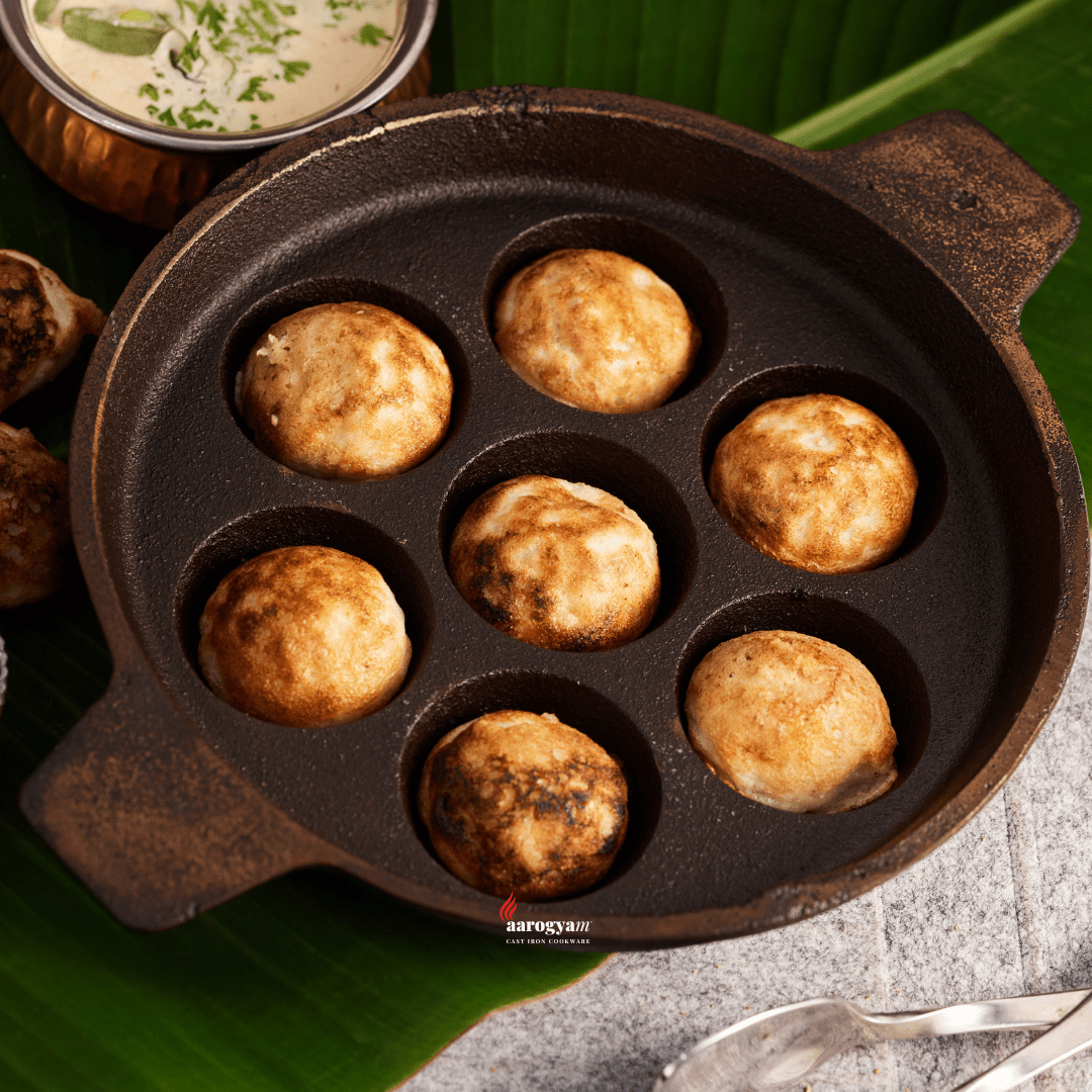 Cast iron mold with fried dough balls on a green leaf background