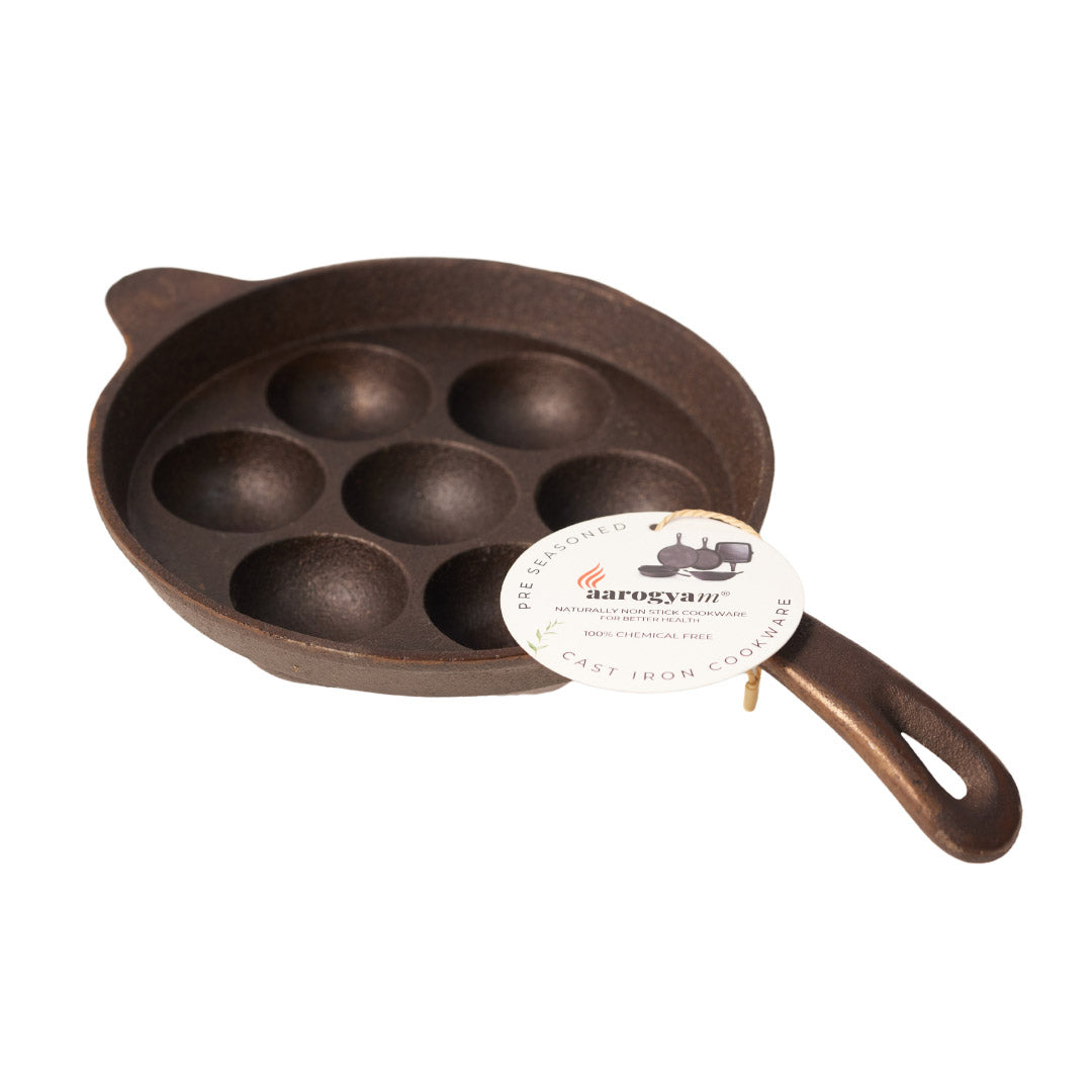 Cast iron pan with multiple round depressions on a white background