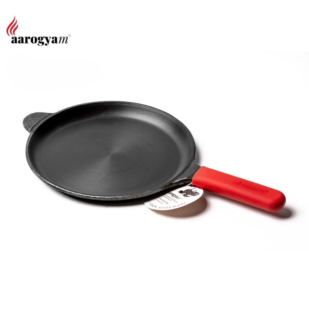 Black frying pan with a red handle on a white background, featuring the 'aarogya' brand.