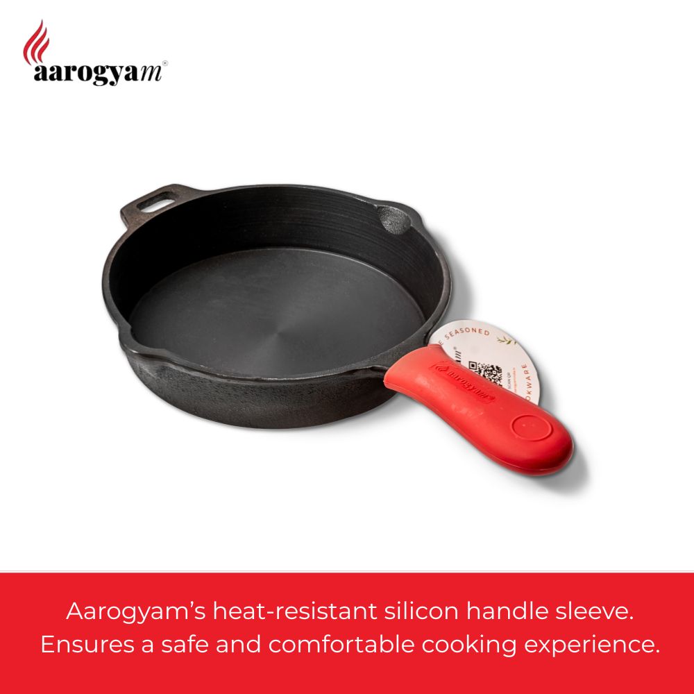Black cast iron skillet with a red heat-resistant silicone handle sleeve on a white background, featuring the Aarogya brand.