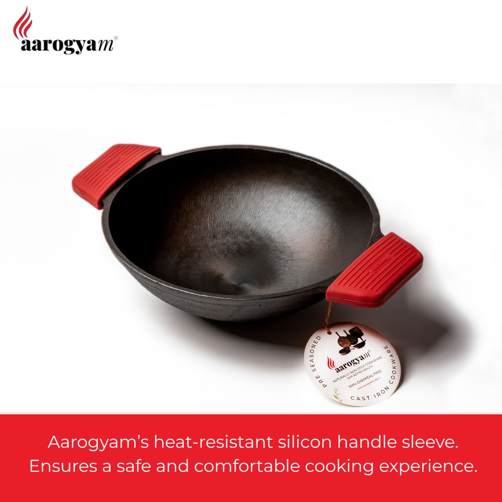 Black frying pan with red heat-resistant silicone handle sleeves on a white background, featuring Aarogya brand.