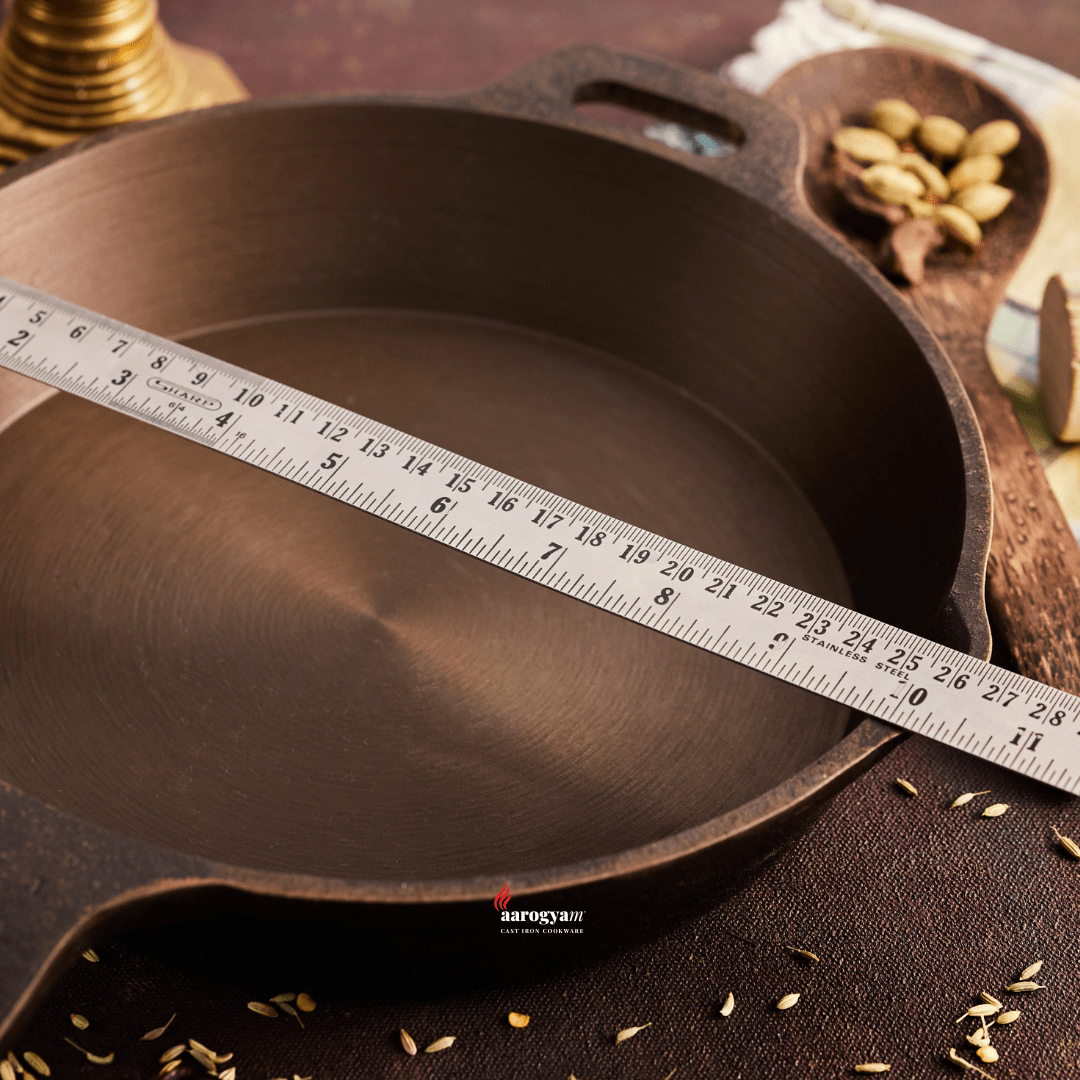 Cast iron skillet with a measuring tape for scale on a wooden surface.