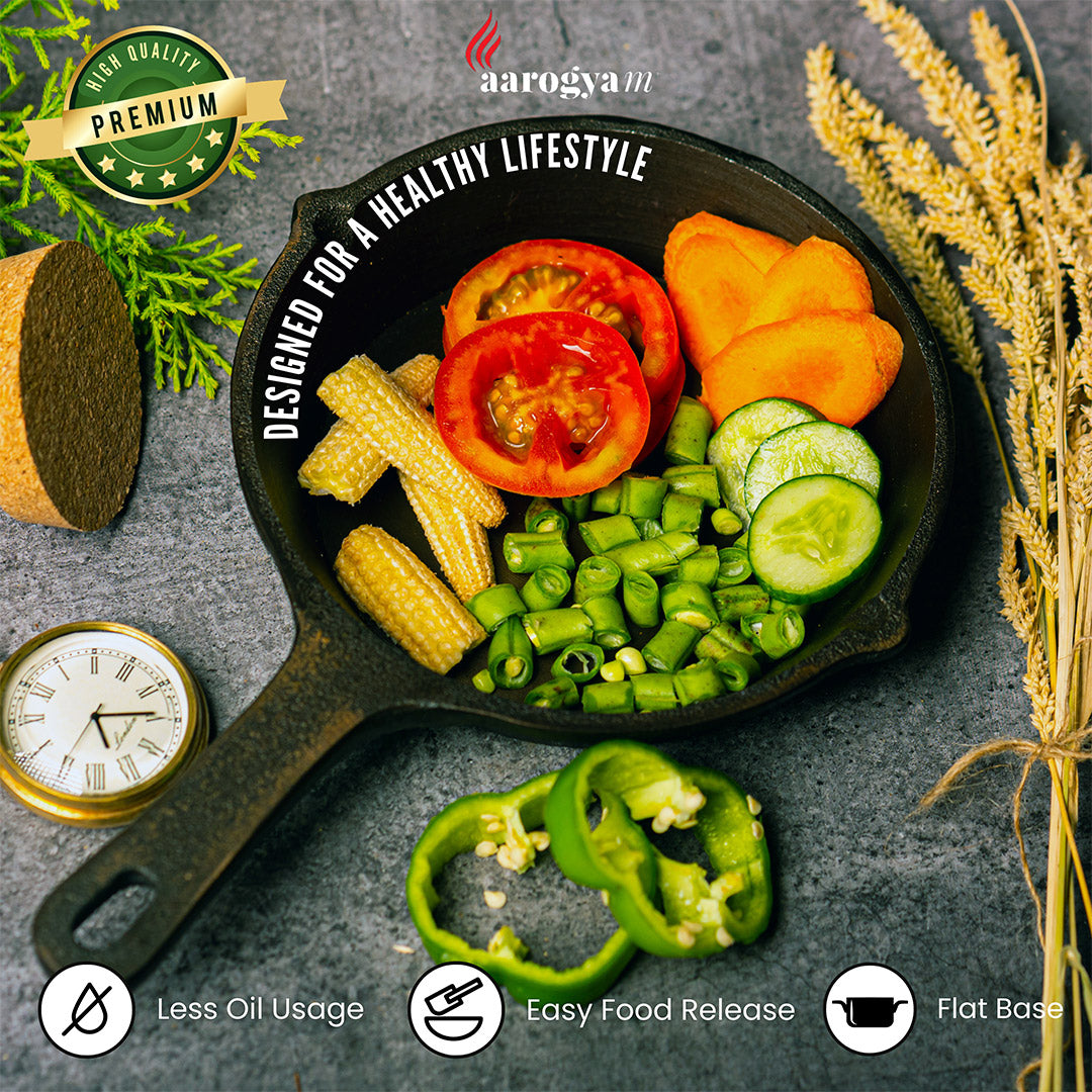 Cast iron skillet with fresh vegetables on a gray surface, featuring the Aarogya brand.