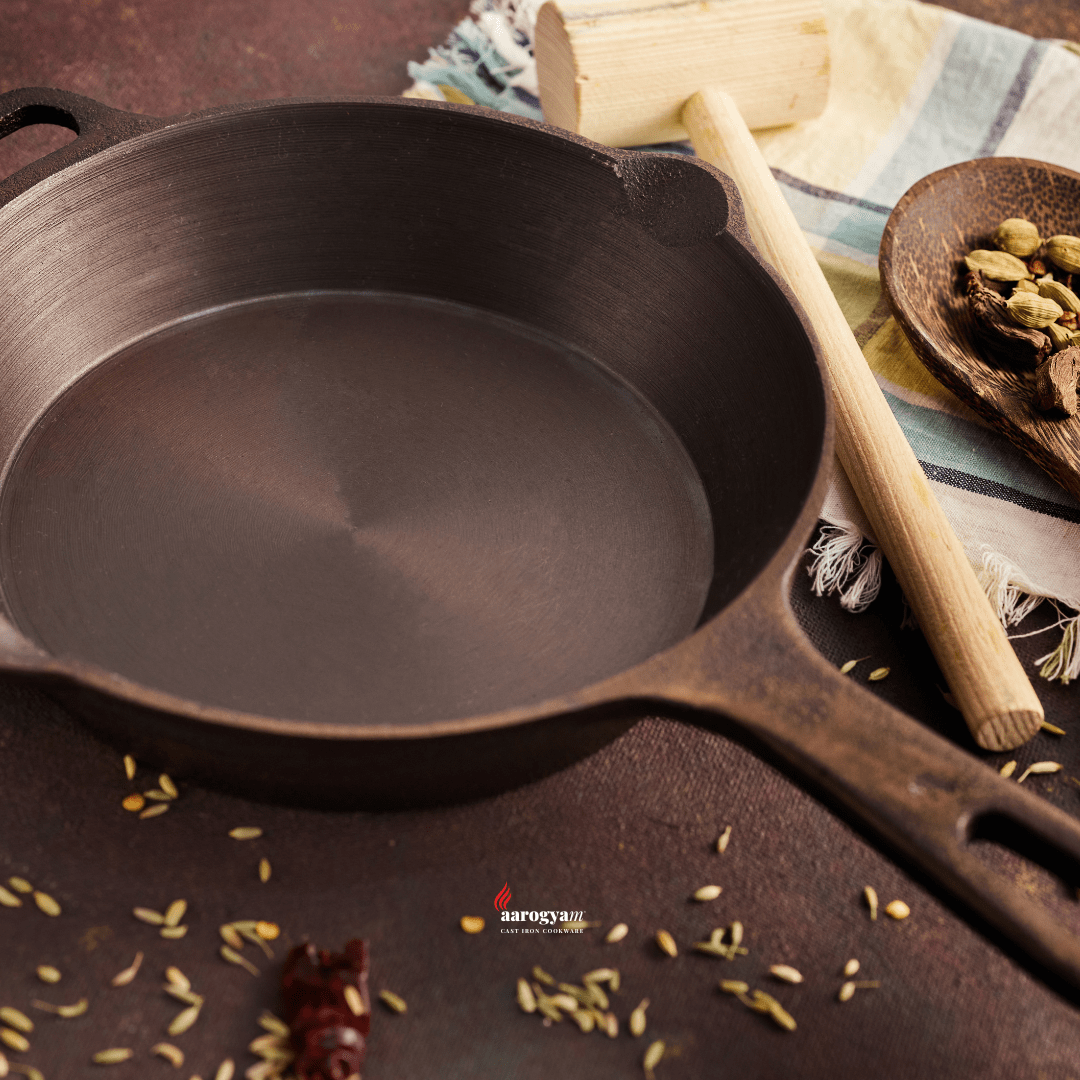 Cast iron skillet on a dark surface with spices and a wooden spoon