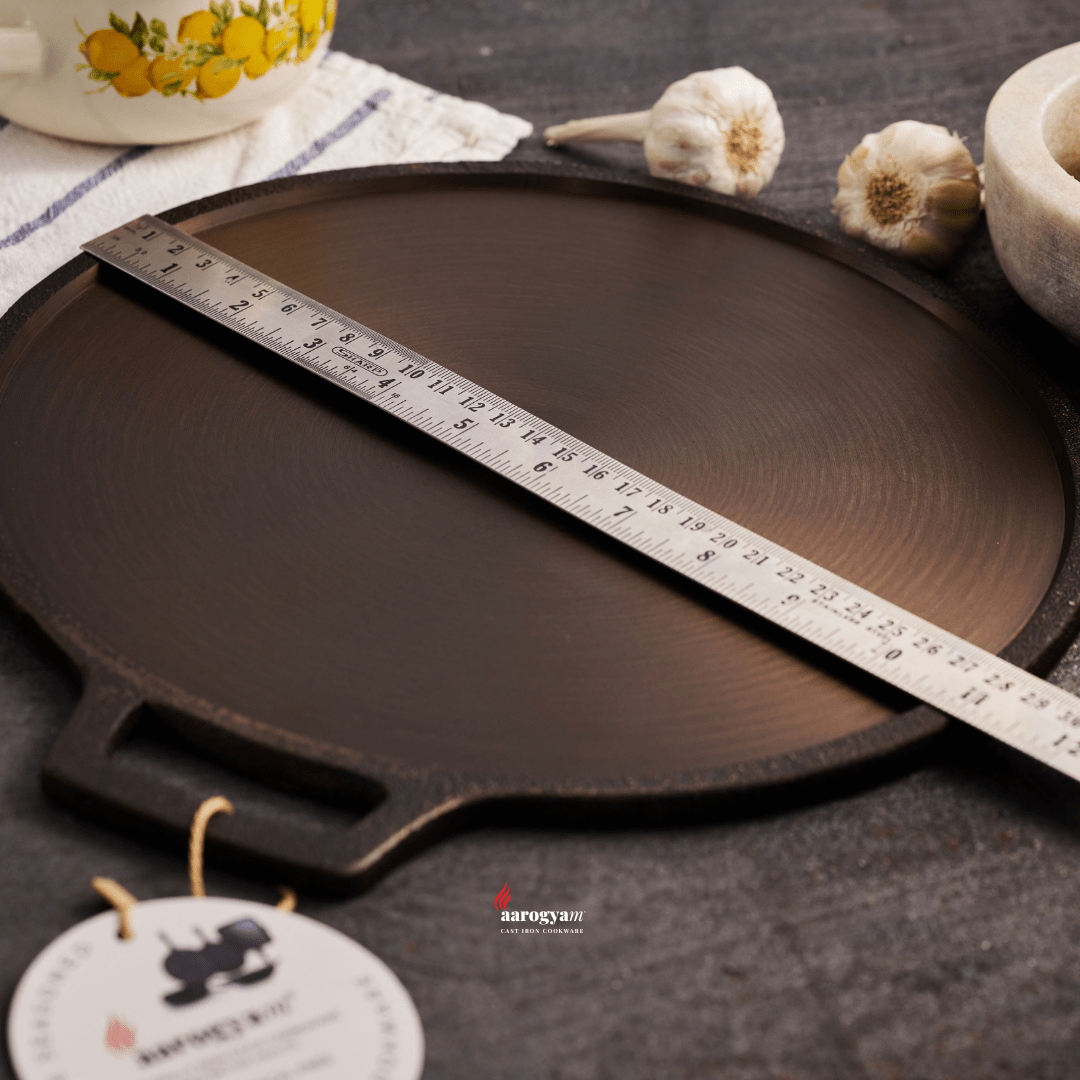 Black round pan with a ruler for measurement on a dark surface, with a brand tag visible.
