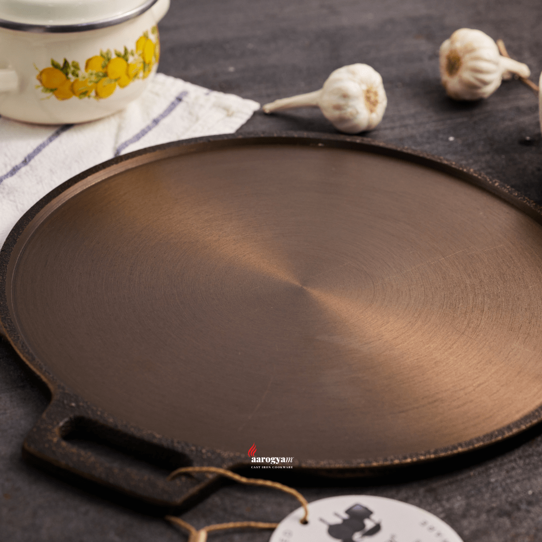 Cast iron skillet on a dark surface with a decorative cup and garlic in the background