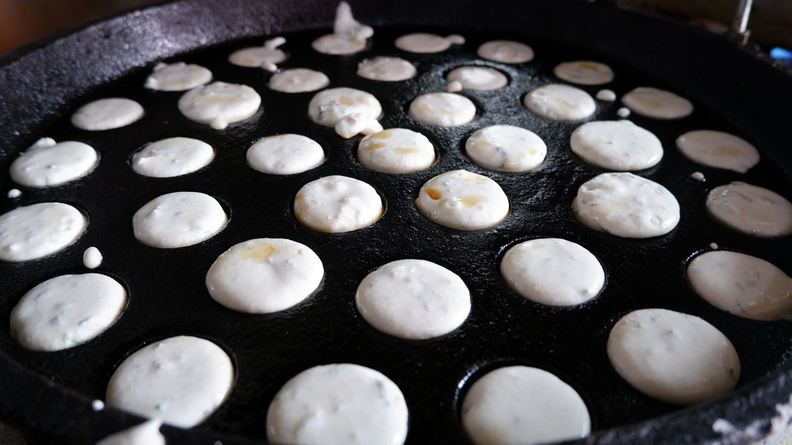 Small pancakes cooking on a black griddle