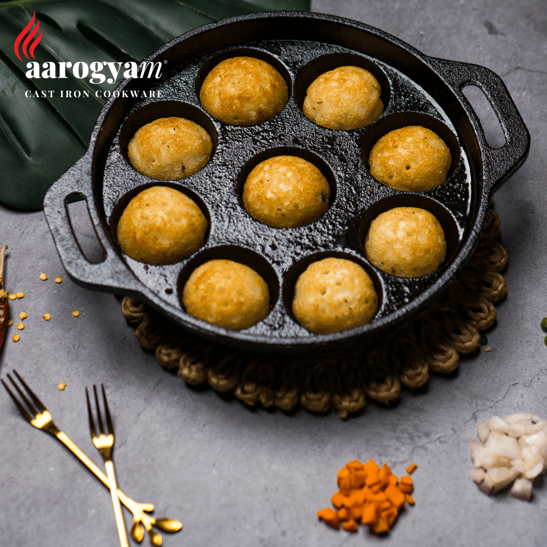 Cast iron cookware with baked items on a gray surface, featuring the brand 'aarogyam'.